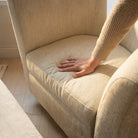 Hand pressing the seat cushion to show the supportive comfort of the linen-upholstered swivel accent chair.